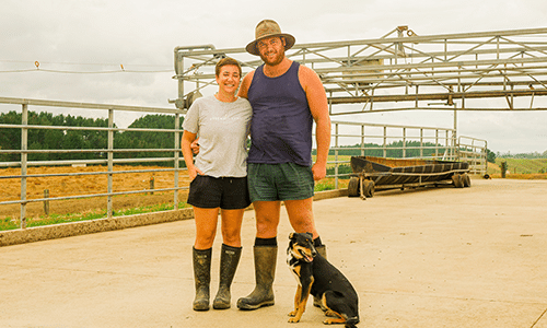Man and woman standing on farm with dog